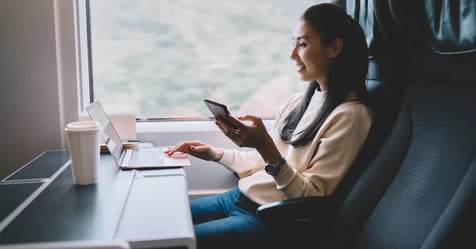 Businesswoman on a train while on her phone and laptop