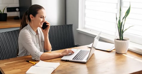 Executive Assistant creating a contingency plan on her laptop while on the phone