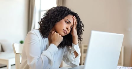 Executive Assistant burnout behind her desk at work, holding her head in confusion
