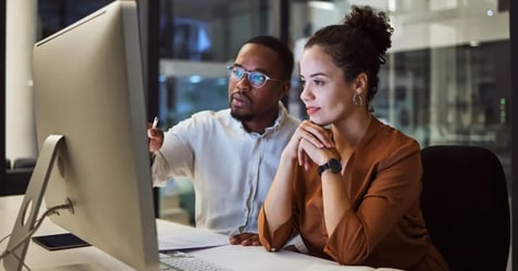Male and female meeting planners in front of a computer in an office