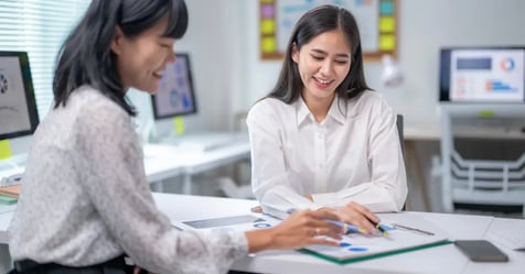 Travel Manager and Executive Assistant working together on in-person meetings in the office