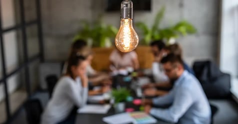 Team meeting to discuss sustainable meeting travel with a lightbulb hanging above them